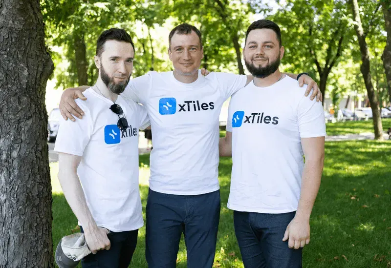 Three xTiles teammates with their arms around each other outdoors