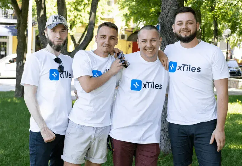 Four xTiles teammates smiling together outdoors